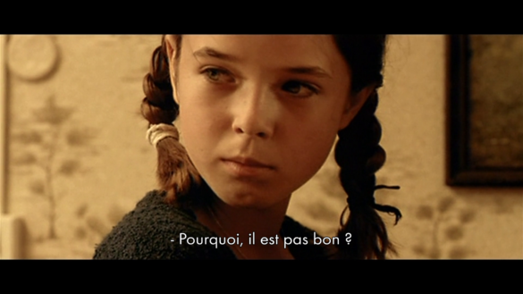 Photogramme extrait du film Sale Battars de Delphine Gleize : le visage d'une jeune fille avec des nattes brunes. Un sous-titrage blanc indique : "Pourquoi, il est pas bon ?"