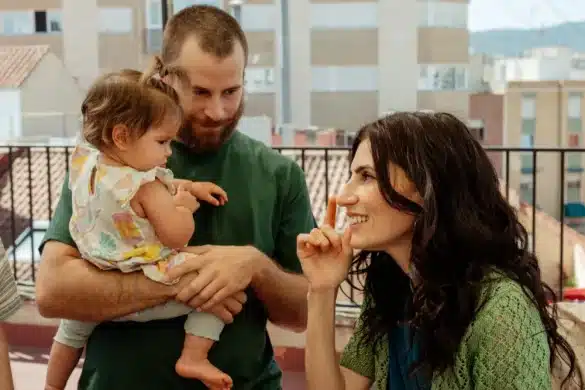 Photo extraite du film Sorda : sur le toit d'un immeuble, un homme porte une petite fille. À leurs côtés, une femme regarde l'enfant en souriant, l'index levé.